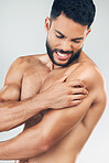 Beauty, body and injury with a man model holding his shoulder in pain in studio on a gray background. Fitness, health and anatomy with a young male suffering with muscle cramp, ache or inflammation