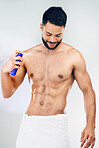 Spray, clean and body of a man with deodorant after a shower against a grey studio background. Wellness, happy and young model with a smile for a fragrance product, health and happiness for hygiene