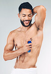 Spray, armpit and man with smile for deodorant against grey studio background. Skincare, smile and strong model with antiperspirant bottle for wellness, skincare and grooming while spraying underarm