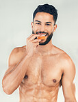 Portrait, fitness and man eating an orange in studio for vitamin c, healthy skin and self care after training. Nutrition, wellness and happy fitness model on a diet enjoys raw fruit after a workout
