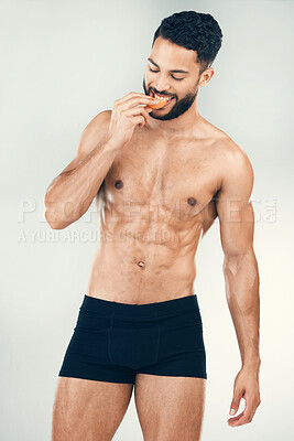 Buy stock photo Health, fitness man and healthy diet while eating an orange for vitamin c, nutrition and wellness with a fit body, smile and underwear. Male athlete model with fruit for energy and self care benefits