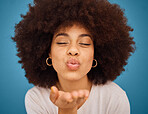 Care, love and black woman blowing kiss with a smile, afro hair and hand against a blue studio background. Happy, beauty and face of a cool, African and young girl model with affection and happiness 