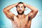 Water splash, skincare and man taking a shower, cleaning and washing body for health, wellness and hygiene against a blue background. Male doing self care routine for skin and face for natural care