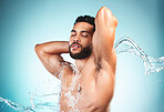 Beauty, shower and water with a man model in studio on a blue background for hygiene or hydration. Wellness, cleaning and splash with a handsome young male washing or cleansing in the bathroom alone