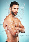 Splash, water and man in hygiene and cleaning portrait, washing body and skin hydration with blue studio background. Topless model wet, skincare and grooming, fresh and clean with wellness.