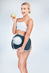 Apple, fitness and woman with a scale for fat loss with a healthy diet after a workout, exercise and training. Weightloss, portrait and happy girl with a weight scale eating fruit for nutrition 