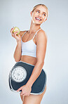 Apple, diet and woman with scale for body health, self care and natural weight loss. Eating healthy food, nutrition lifestyle and wellness exercise training for fat workout in gray studio background 