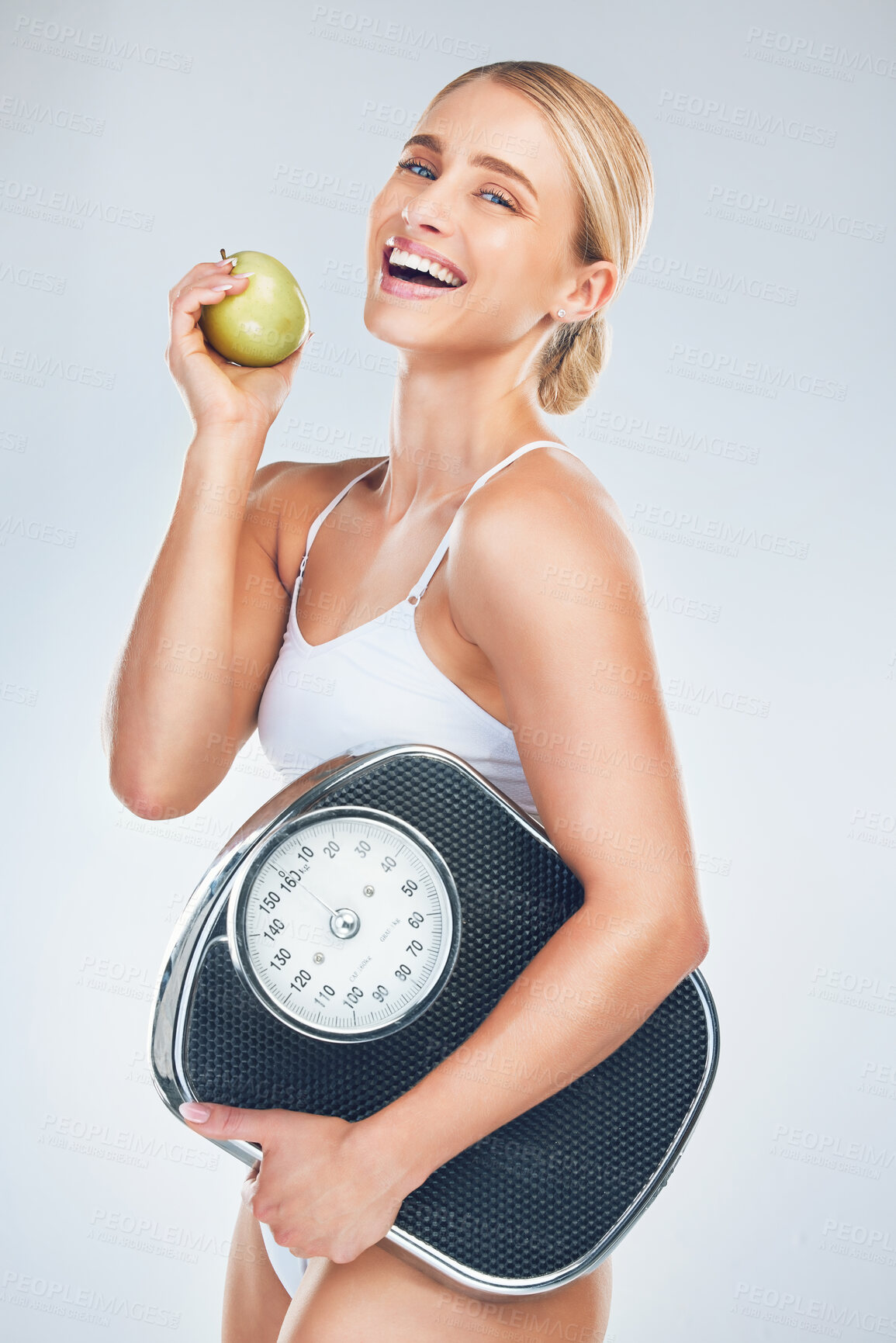 Buy stock photo Apple, diet and woman with a scale to lose weight, training and smile against a grey studio background. Advertising, food and model excited about nutrition, fruit and balance for health of body