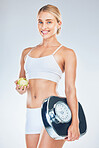 Scale, smile and portrait of a woman with an apple for weightloss against a grey studio background. Health, nutrition and happy young model with fruit and scales for training motivation and wellness