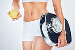 Woman, scale and apple for diet, weightloss or health with fitness, closeup or nutrition by grey background. Model, girl and stomach with fruit, food or balance for goal, vision or wellness in studio