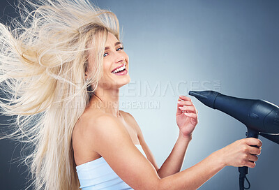 Buy stock photo Beauty, hair care and woman on blue background with hair dryer, smile and healthy blonde salon hair style. Health, wellness and luxury care for happy model hair, color treatment, shampoo and dry hair