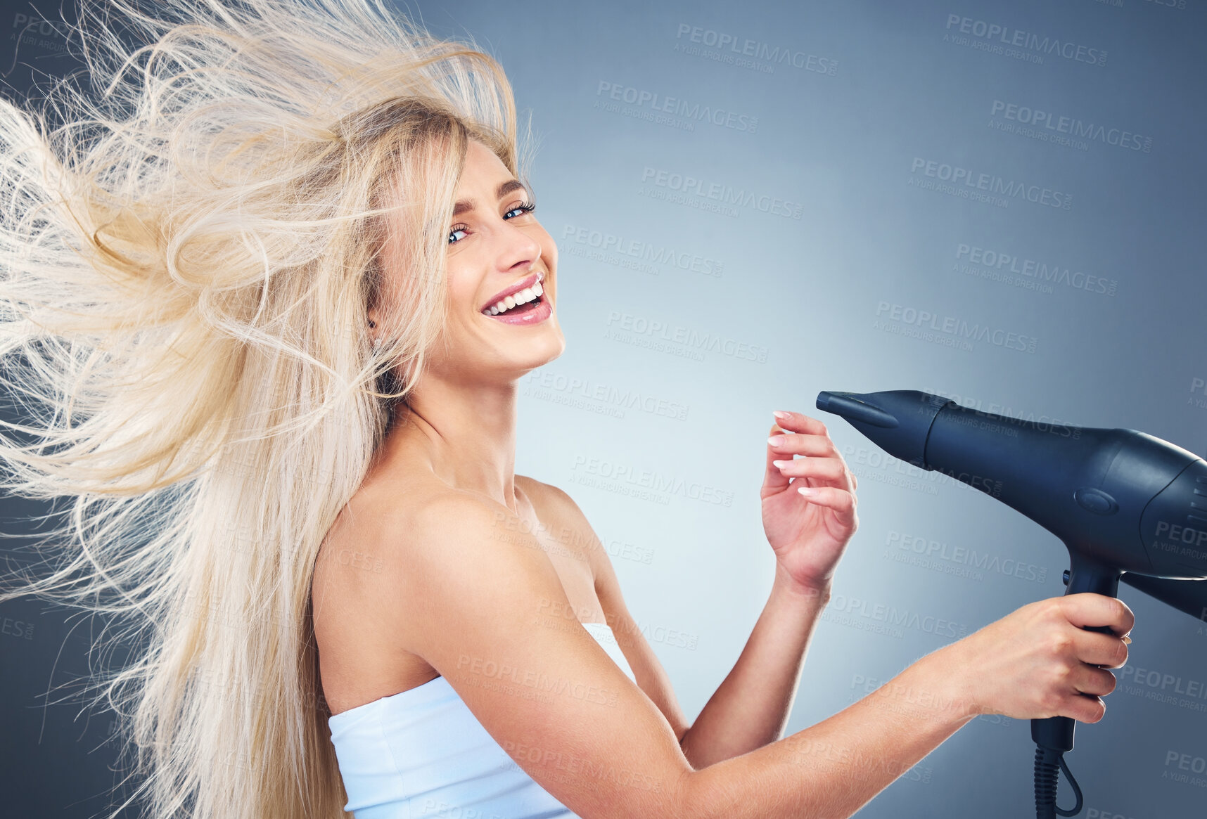 Buy stock photo Beauty, hair care and woman on blue background with hair dryer, smile and healthy blonde salon hair style. Health, wellness and luxury care for happy model hair, color treatment, shampoo and dry hair