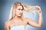 Upset, angry and annoyed woman with hair problem or style issue on a grey studio background. Damage, bad and expression of female unhappy with blonde hair loss for advertisement on a backdrop
