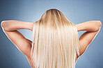 Beauty, hair and haircare with blonde woman styling hairstyle on a grey studio background for grooming. Hair care, hygiene and hair style for contemporary female from the back on a gray backdrop