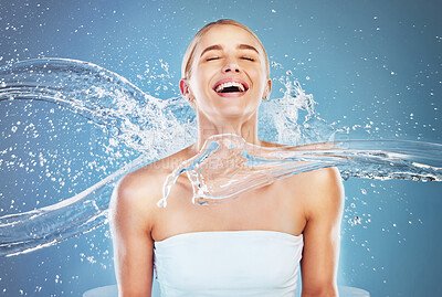 Buy stock photo Hydration, happy and woman with a water splash for body cleaning, skincare and dermatology against a blue studio background. Wellness, beauty and excited model with facial care from a spa liquid