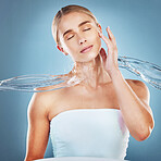 Beauty, skincare and woman with a splash of water for a natural facial routine in studio. Hygiene, cosmetic and healthy young model with clean face or skin treatment while isolated by blue background