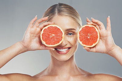 Buy stock photo Grapefruit, skincare and face of a woman with smile for health, wellness and healthcare with food against a grey studio background. Nutrition, happiness and model with fruit for body detox and diet