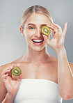 Happy studio portrait, woman with kiwi for skincare wellness, health and beauty by grey wall. Cosmetics model, girl with smile, fruit and self care for healthy facial, skin or vitamins by background
