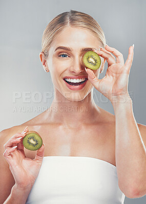 Buy stock photo Happy studio portrait, woman with kiwi for skincare wellness, health and beauty by grey wall. Cosmetics model, girl with smile, fruit and self care for healthy facial, skin or vitamins by background