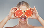 Woman, hands and fruit eyes in skincare holding grapefruit for healthy wellness against a grey studio background. Happy female in beauty cosmetics with juicy or fruity smile for vitamin C nutrition