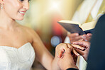 Wedding, marriage and putting ring on finger of bride in celebration of love, romance and commitment. Young couple getting married in church with groom giving jewellery to wife in wedding ceremony