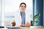 Portrait of doctor working in her office at hospital with healthcare, medicine or medical paperwork. Serious, woman and professional surgeon sitting at a desk doing research on health care at clinic.