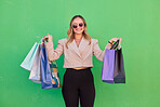 Fashion, shopping bag or woman in studio with green background for retail, luxury or designer gift or clothes. Portrait, model or rich girl happy for discount, smile or retail boutique product brand