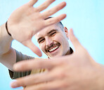 Hands frame, portrait and smile of man in studio isolated against a blue background. Face, fashion and happy, comic and smiling carefree male with hand sign or gesture enjoying quality time alone.