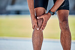 Runner, knee injury and pain in legs on field, track or sports at training, workout or exercise. Black man, sport and knee pain emergency in running for health, wellness or muscle development outdoor