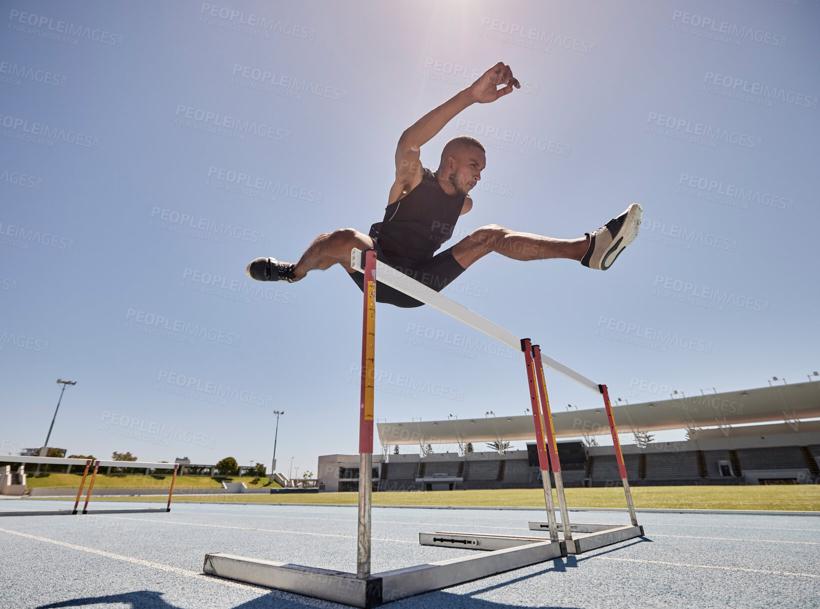 Buy stock photo Running, jump and athlete hurdle for a speed exercise, marathon or runner training in a stadium. Short health, cardio and man run fast for a jumping competition or fitness workout for sports wellness