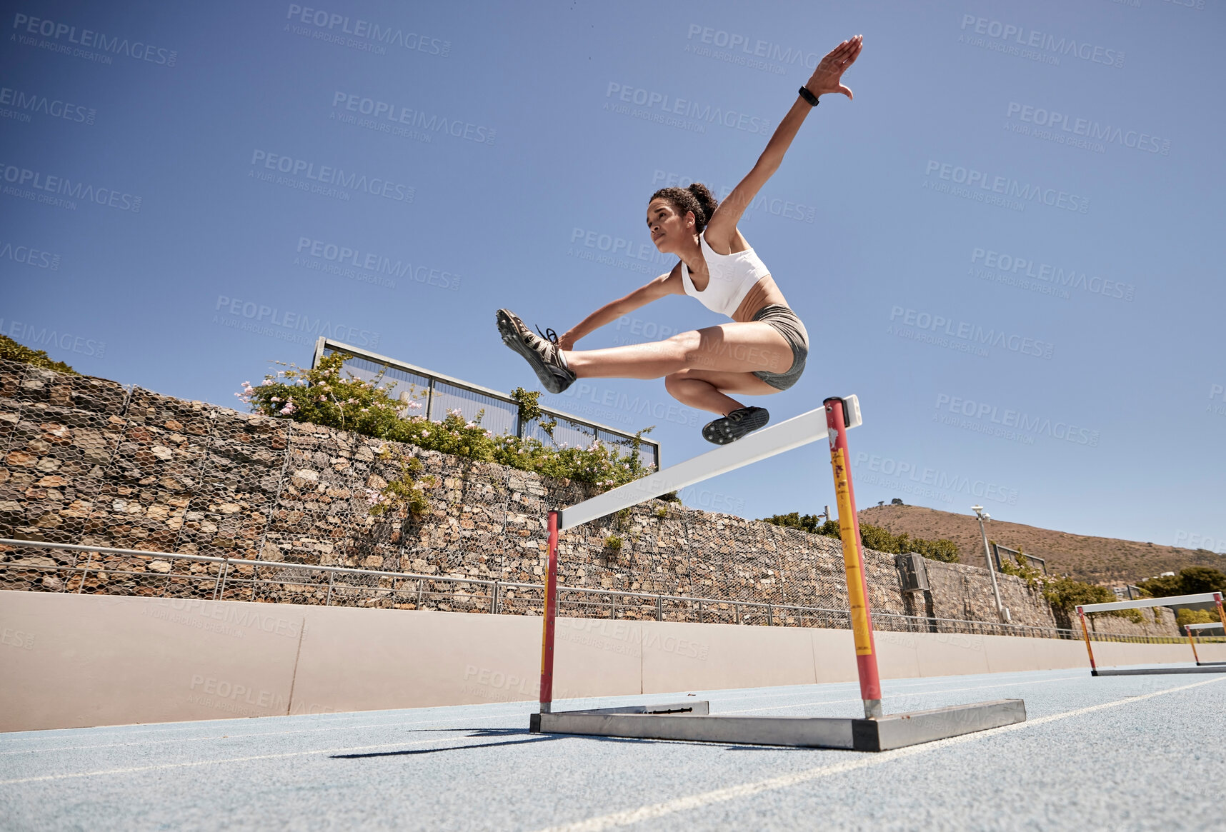 Buy stock photo Runner, fitness and girl stadium jump for athlete hurdle training, workout or competition race. Challenge, running and power performance of athletic black woman on sports ground with sky mockup.
