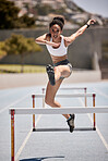 Fitness, hurdles and athlete jumping on track at an outdoor stadium for cardio workout. Sports, running and woman doing athletics on field for training and exercise with energy, motivation and speed.