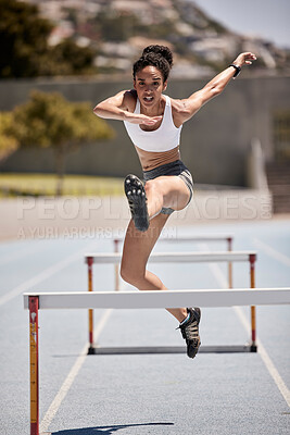 Buy stock photo Fitness, hurdles and athlete jumping on track at an outdoor stadium for cardio workout. Sports, running and woman doing athletics on field for training and exercise with energy, motivation and speed.