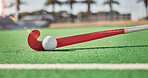 Closeup, hockey and hockey stick with ball on field in sunshine for sport, contest or competition in summer. Sports, turf pitch and artificial grass on ground for exercise, workout and training game