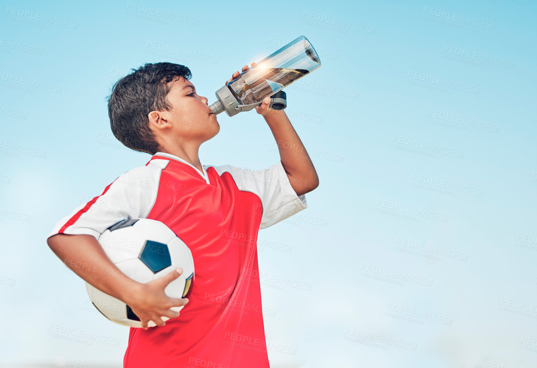 Buy stock photo Training, sports and football with child drinking water for fitness, health or endurance exercise. Wellness, summer and workout with young soccer player and bottle for electrolytes, relax and thirsty