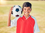 Boy portrait, field and soccer ball with smile for sport, fitness or training at soccer game, contest or competition. Athlete kid, football and happy with ball on shoulder for sports outdoor on grass