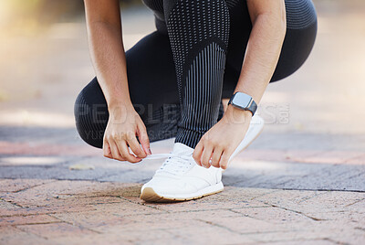 Woman, hands and shoelaces tie for fitness, workout or training on city road, street or urban location. Zoom, runner or sports athlete running shoes on concrete ground for marathon or cardio exercise