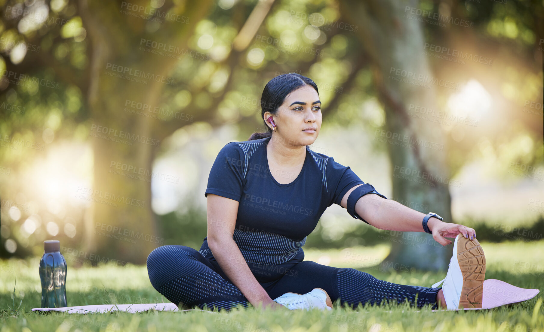 Buy stock photo Woman, fitness stretching and nature park listening to music after a runner exercise and sports. Real plus size athlete from India stretch legs ready for wellness, health workout and running on grass