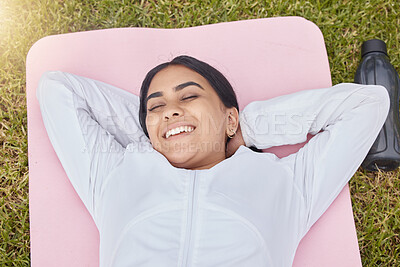 Happy woman lying on exercise mat in park, garden and grass field for peace, sleep and motivation for workout, training and fitness. Indian girl rest on yoga mat in nature, wellness and healthy life