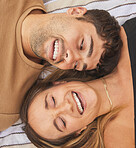 Above, love and couple with a smile on a blanket at a park during a date, holiday or picnic. Comedy, happy and face of a funny man and woman laughing on a vacation together on the ground in nature