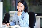 Asian woman, call center and portrait while writing in notebook for phone call, customer service or help. Woman, office with smile, happy and working in customer support, consulting or telemarketing