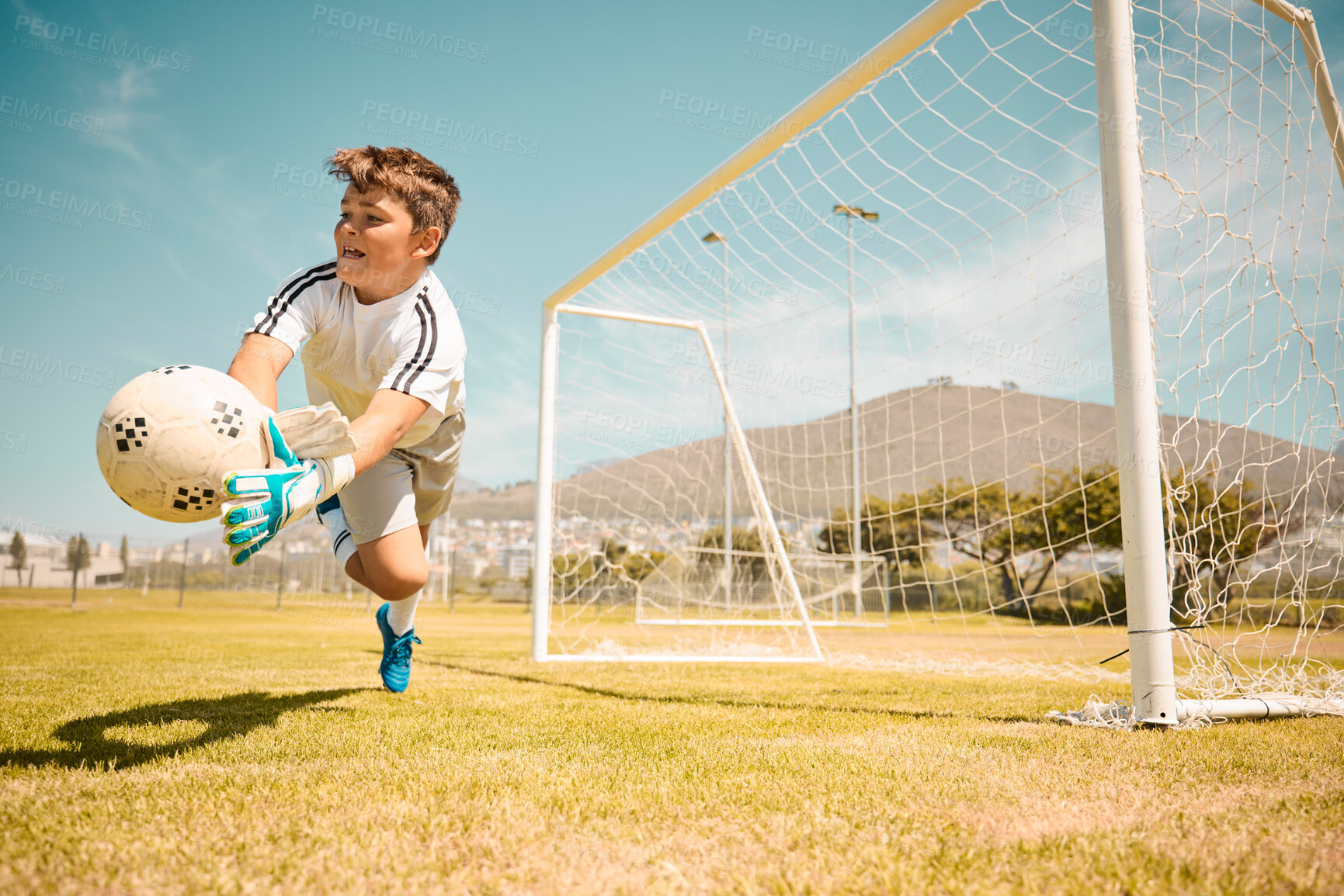 Buy stock photo Football, boy goalkeeper and jump, saving ball from goals at outdoor sports field. Soccer, kid and competition game with fitness, goal keeper and soccer ball on grass, success and action to save goal