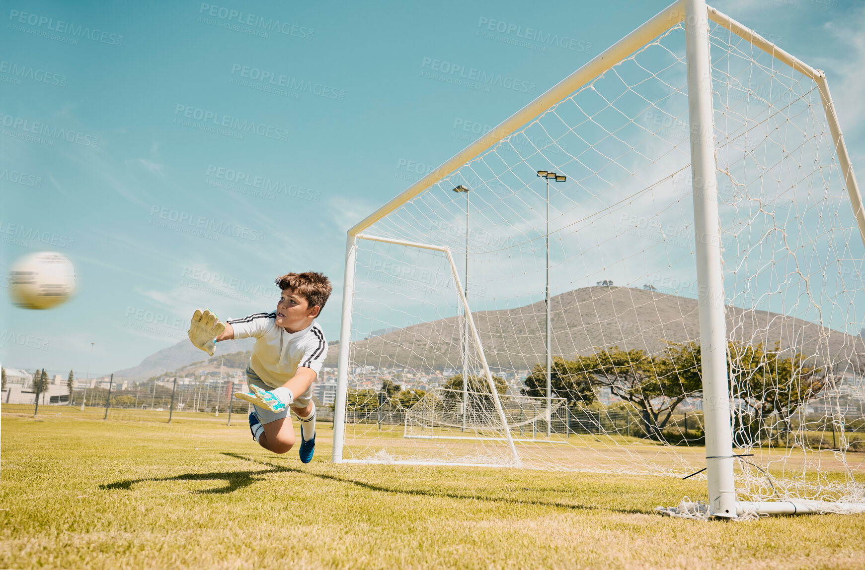 Buy stock photo Soccer, sports and children with a goalkeeper saving a shot during a competitive game on a grass pitch or field. Football, kids and goal with a male child diving to save or stop a ball from scoring