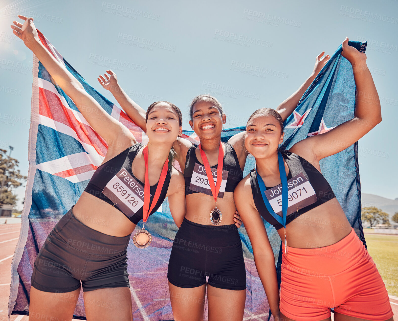 Buy stock photo Athlete, champion and winning group of women holding new Zealand flag and medal after competition, marathon and running at stadium. Portrait of diversity female runners happy about win or achievement