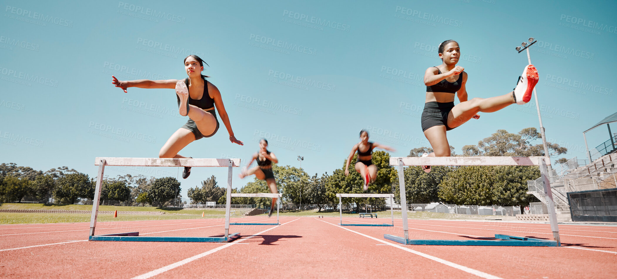 Buy stock photo Woman, jumping and hurdles in competitive sports training, exercise or athletics on the stadium track. Women in sport fitness competition for hurdle jump, running and fast cardio exercising outside