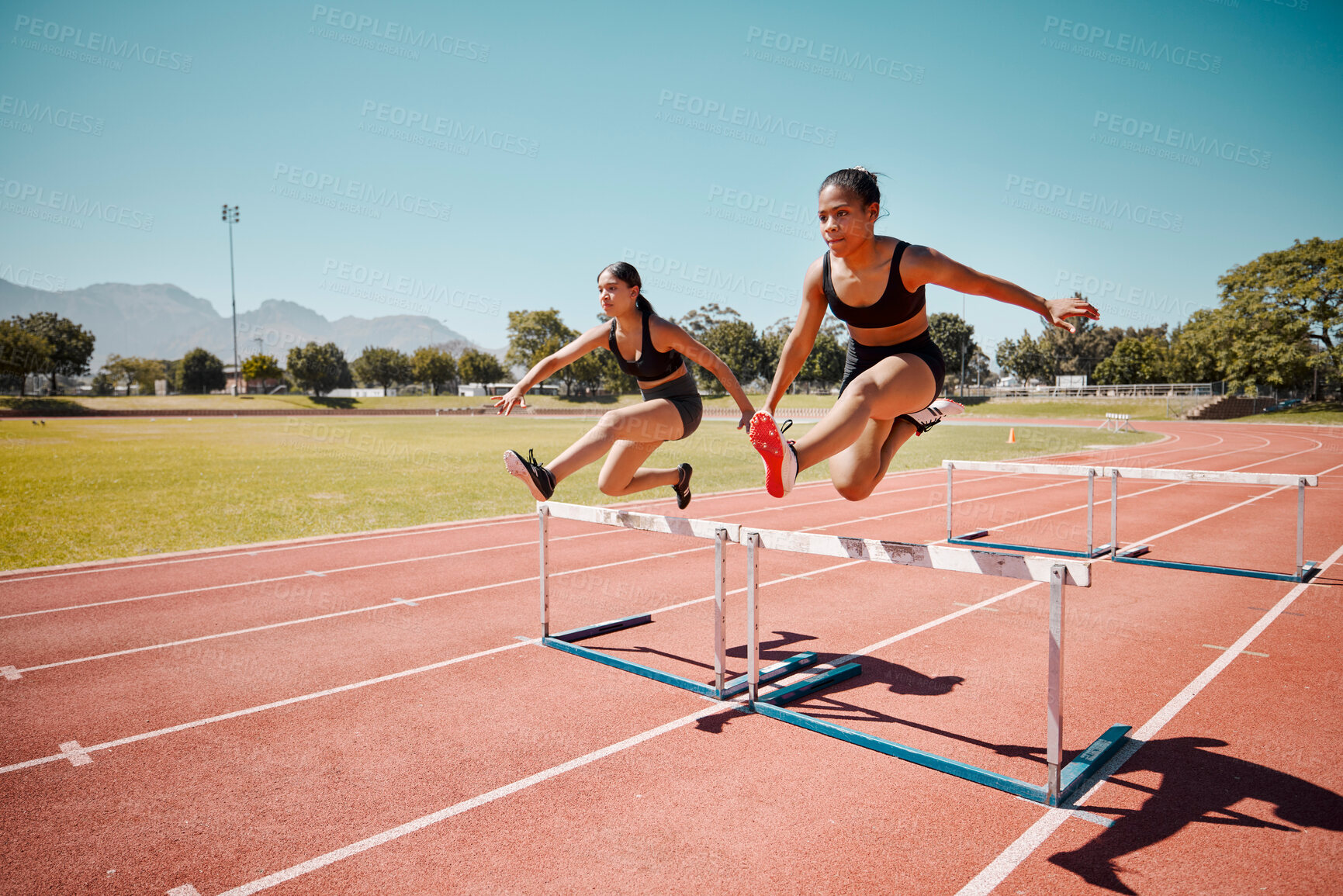 Buy stock photo Sport, jump and women runner doing hurdles on stadium track, athlete running race and fitness training outdoor. Practice, workout and sports, speed and agility for exercise and cardio motivation.