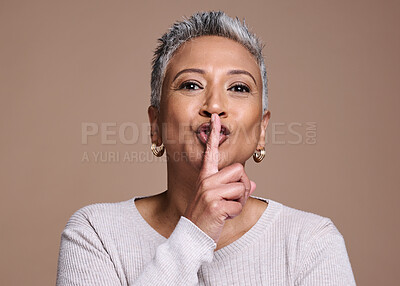 Buy stock photo Face, skincare and secret with a senior woman in studio on a brown background with her finger on lips. Portrait, quiet and whisper with a mature female in secrecy about anti aging treatment or care 