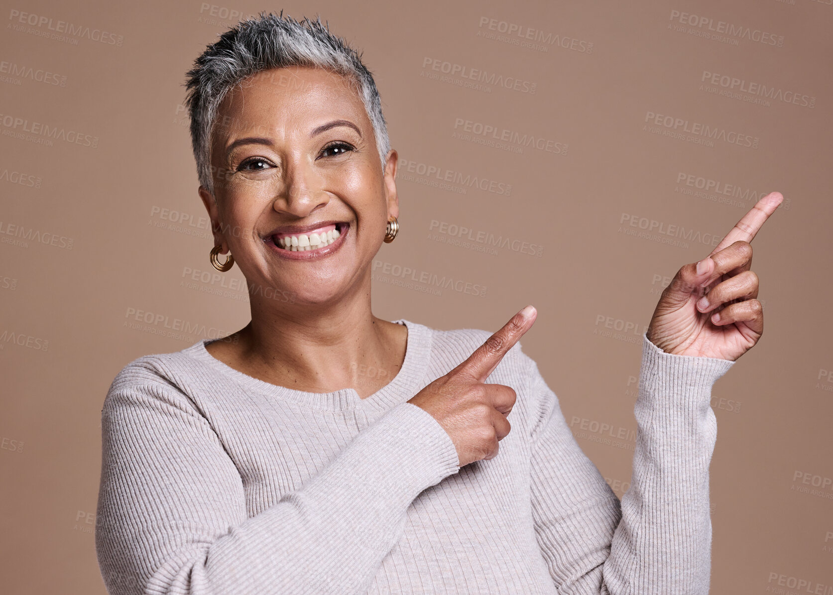 Buy stock photo Woman, smile and happiness in studio for advertising free space, promo or mockup on a brown background for cosmetics, makeup or fashion. Face portrait of a mature model pointing finger at mock up
