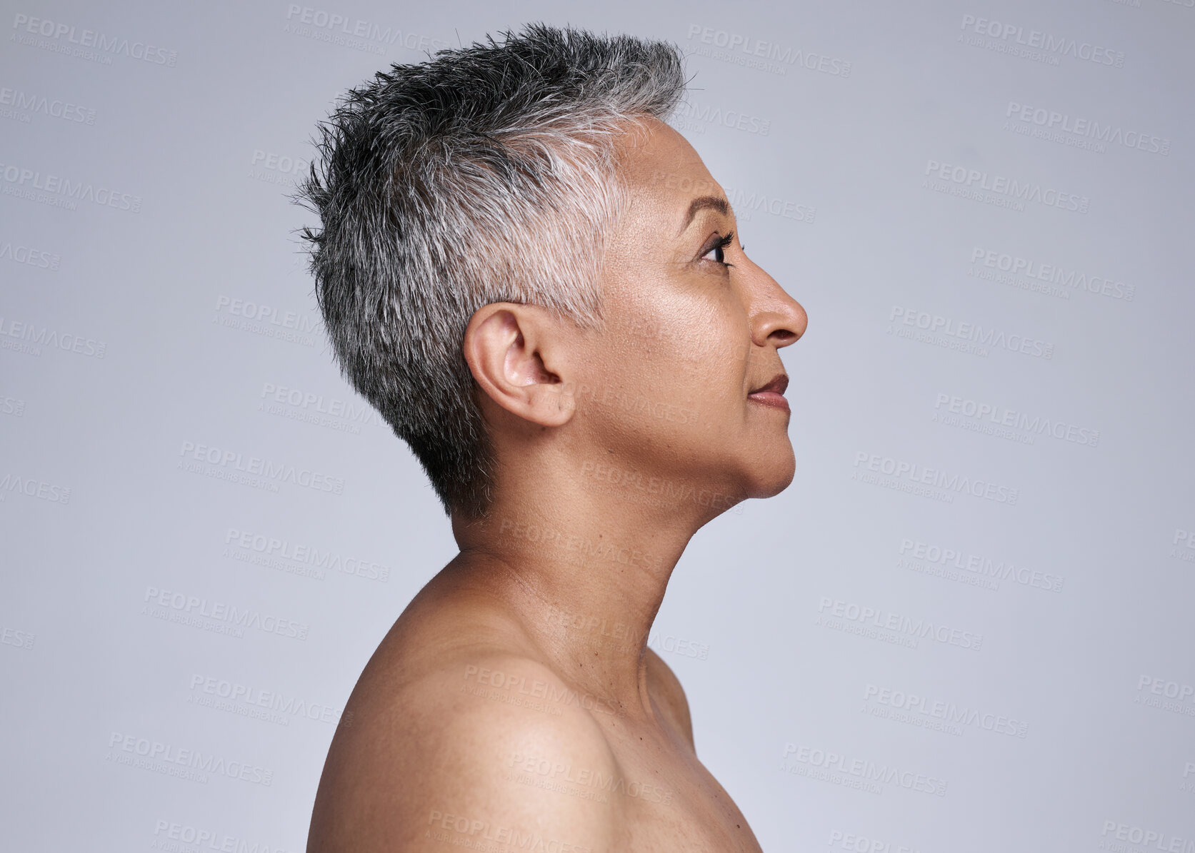 Buy stock photo Mature woman, face and skincare glow on gray studio background in plastic surgery, body dermatology or cosmetology preparation. Indian beauty model, grey hair or makeup cosmetics on mock up profile