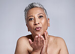 Beauty, mature woman blowing a kiss and cosmetics in studio background portrait. Skincare, happy senior lady kissing air and sending love in celebration of life, wellness and happiness in retirement.